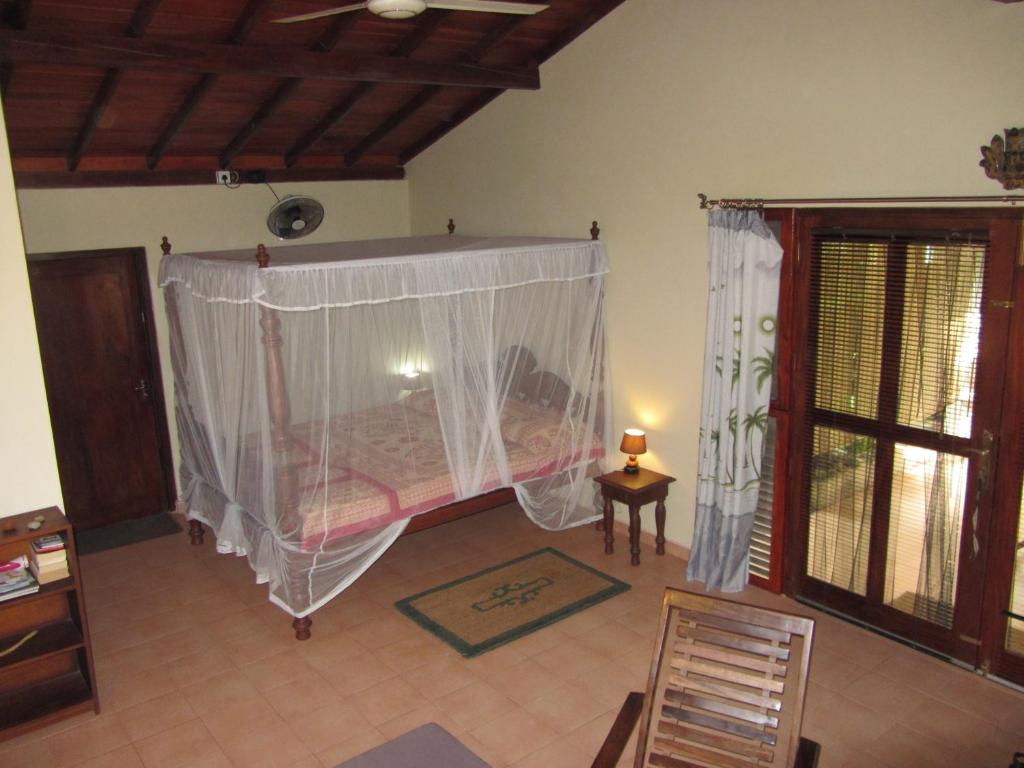 a bedroom with a bed with a mosquito net at Mallis Guesthouse in Habaraduwa