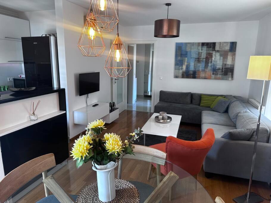 a living room with a couch and a table with flowers at Apartman Pionirska dolina in Sarajevo