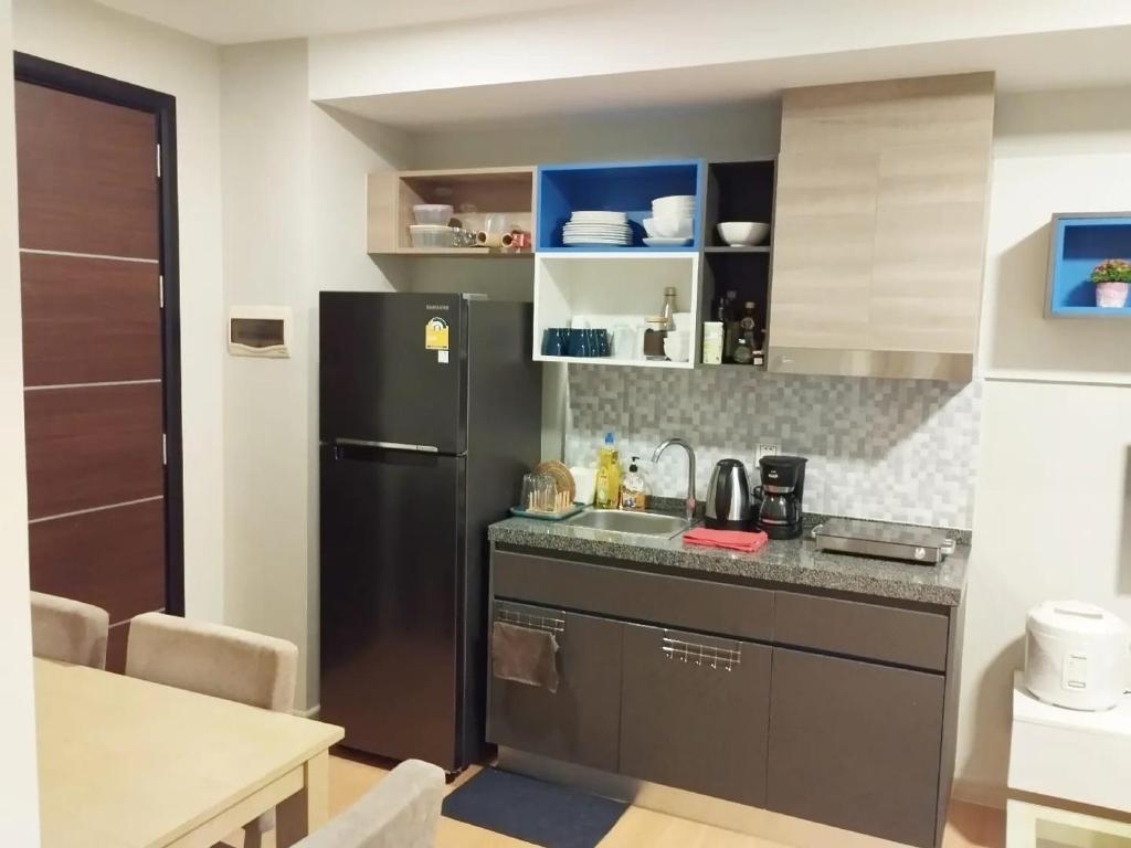 a kitchen with a black refrigerator and a table at AMI POLARIS 23 Apartment-Residence in Phnom Penh