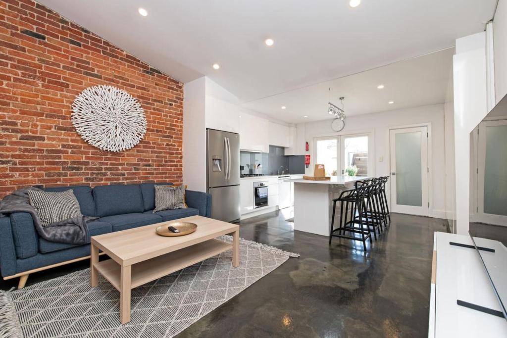 a living room with a blue couch and a brick wall at Lovely and Spacious 2-bedroom home in Norwood in Adelaide