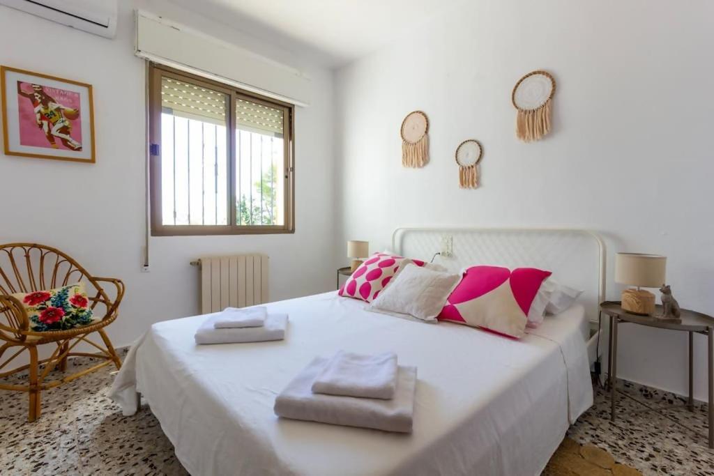 1 dormitorio con 1 cama blanca grande y toallas. en La Villa del Sol, en Oliva