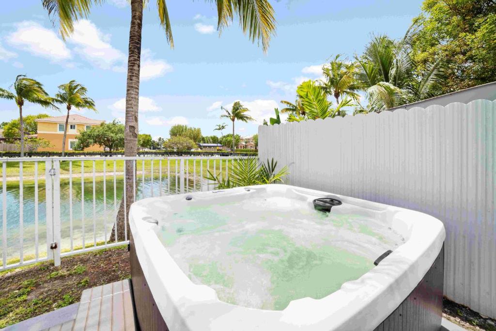 d'une baignoire blanche installée à côté d'une clôture blanche. dans l'établissement Ohana House Jacuzzi Pool and Ping Pon Terrace, à Homestead