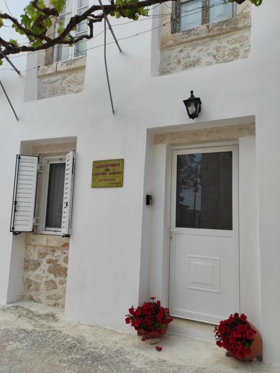 een wit huis met een witte deur en bloemen bij Xenonas "Alexandra's Coffee House" in Volímai