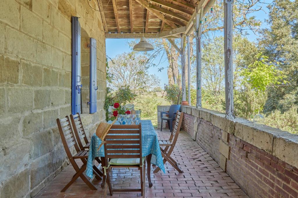 einen Tisch und Stühle auf der Veranda eines Hauses in der Unterkunft Cambes la Douce - Maison de vacances à la campagne in Cambes