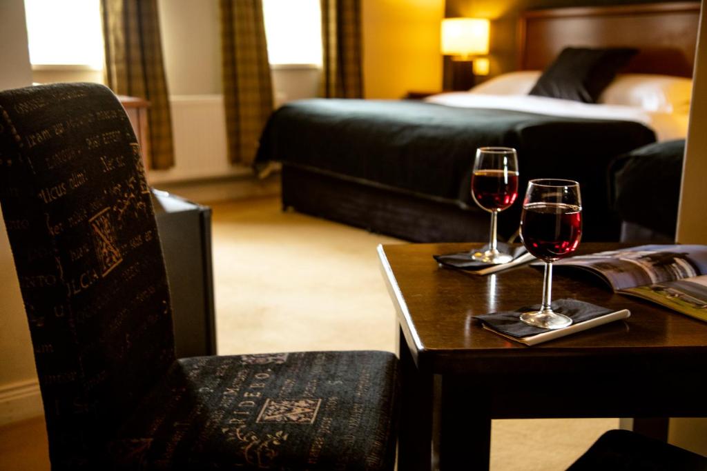 twee glazen wijn op een tafel in een hotelkamer bij Donegal Manor in Donegal