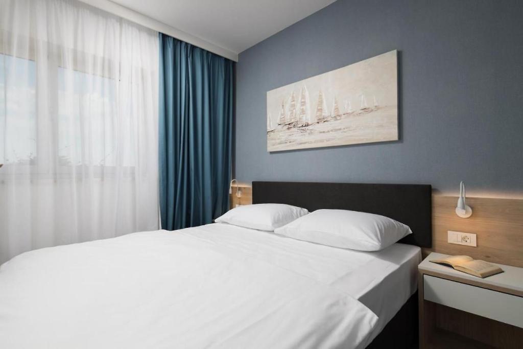 una camera da letto con un grande letto bianco e una finestra di Garden Palace Pool Deluxe Apartment a Umag (Umago)