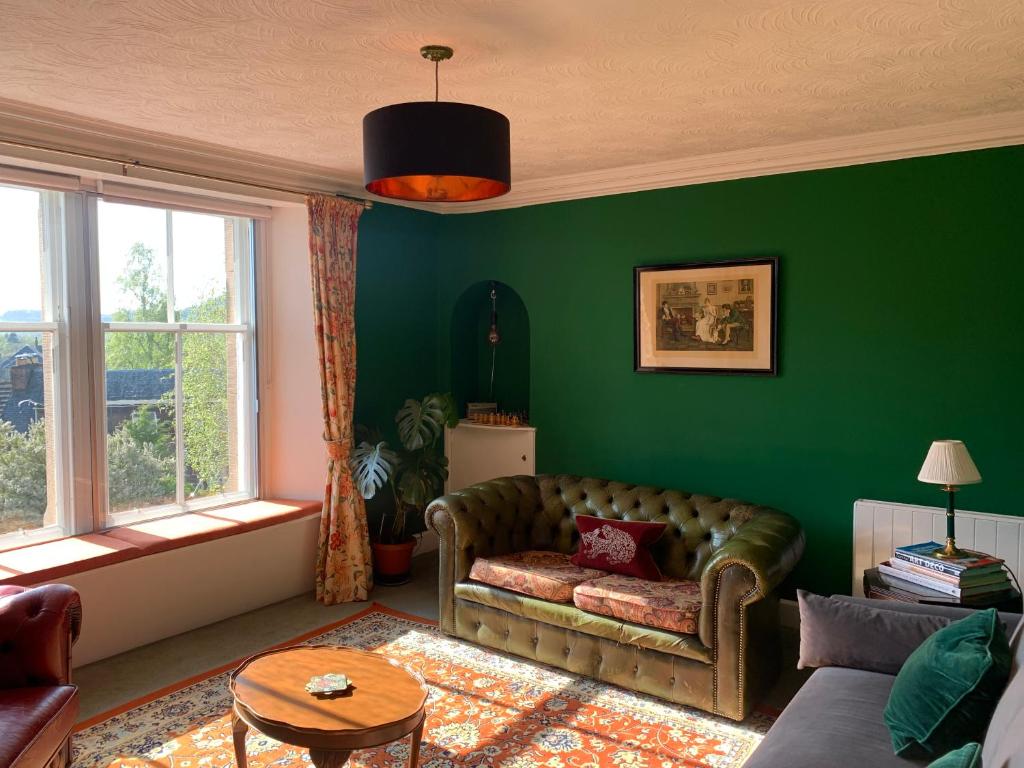 uma sala de estar com um sofá e uma parede verde em Squirrel Away At Leven House em Crieff