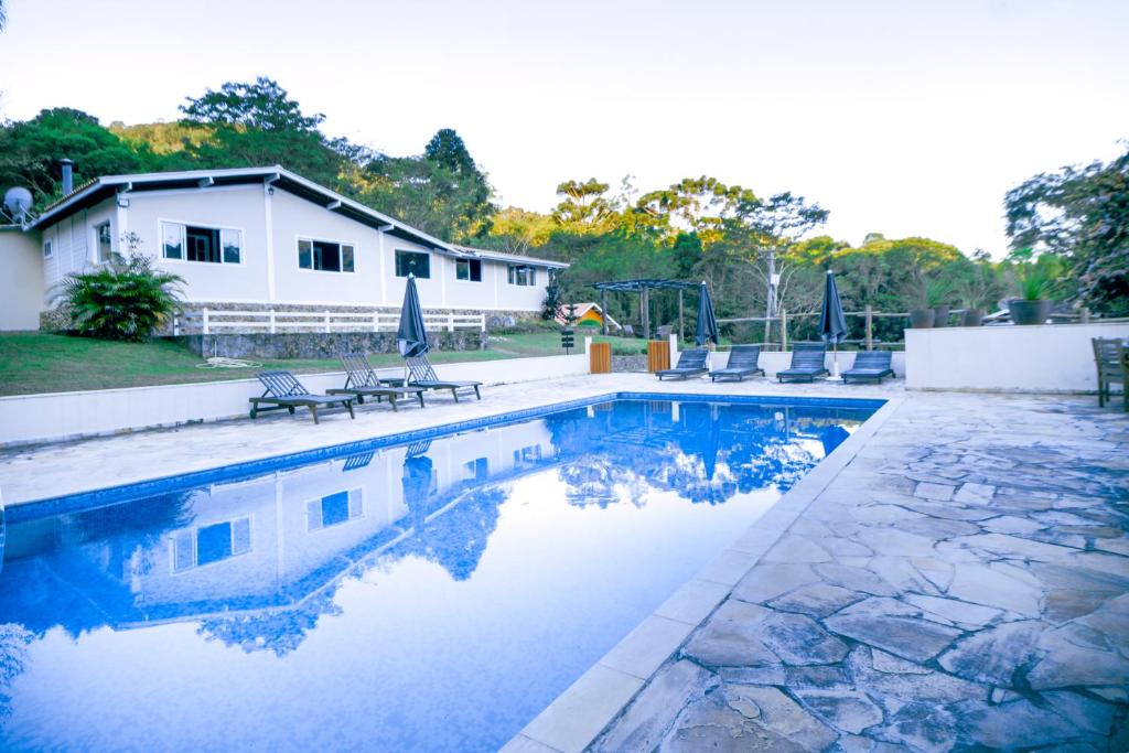 una piscina con sillas y una casa en VELINN Pousada Highland, en Santo Antônio do Pinhal