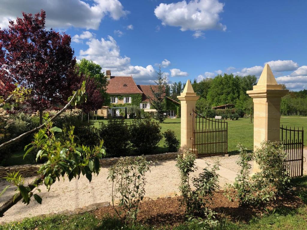 un portail dans une cour avec une maison en arrière-plan dans l'établissement Studio indépendant, à Anglars-Nozac