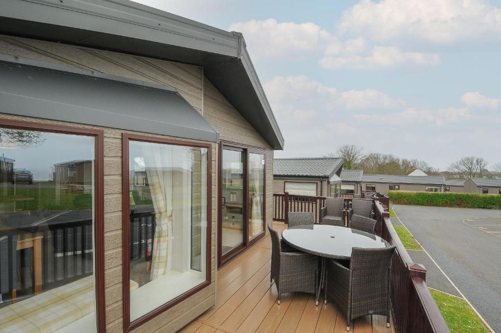 a patio with a table and chairs on a deck at Lodge 71 at Riviera Bay Coastal Retreat in Brixham