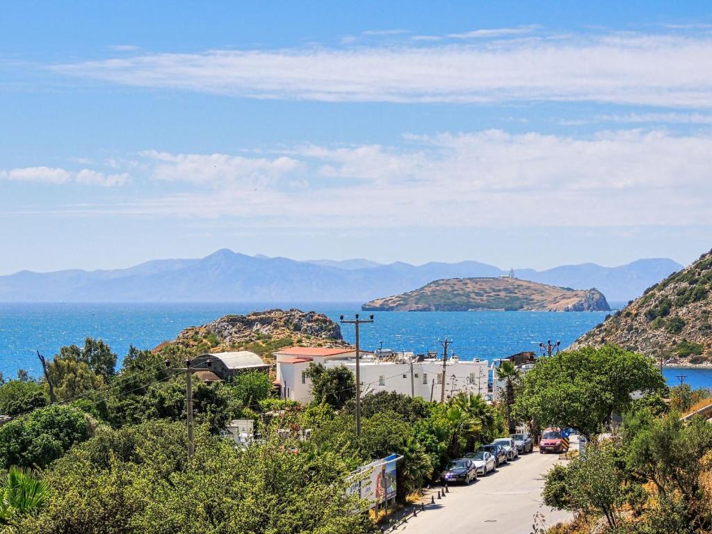 a street with cars parked on a hill next to the ocean at Oza Boutique hotel in Gümüşlük