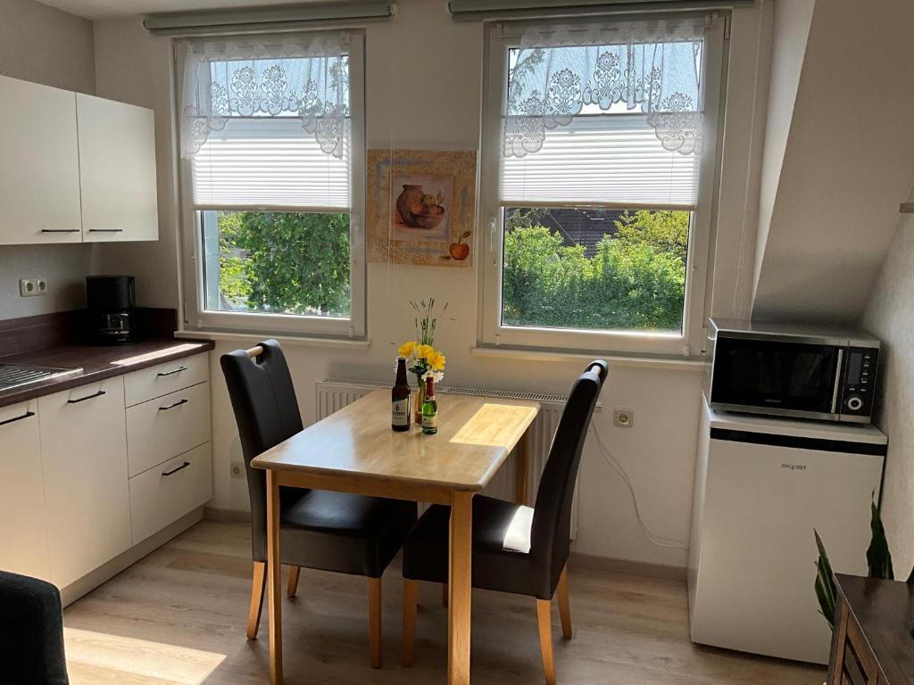 eine Küche mit einem Holztisch und Stühlen sowie 2 Fenstern in der Unterkunft Apartement Meerblick in Wunstorf