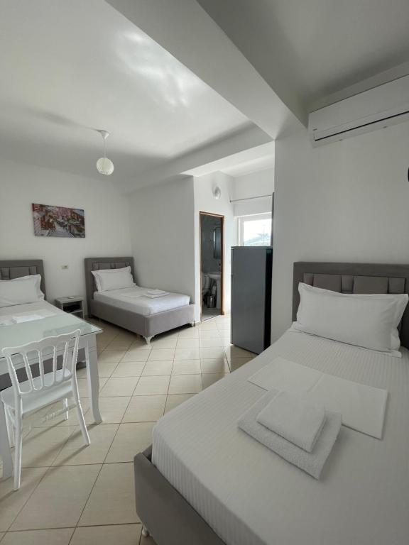 Joni Apartments في كساميل: غرفة بيضاء بسريرين وطاولة