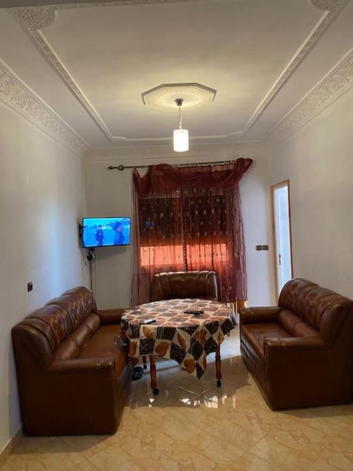 Oulad ZenatiにあるAppartement familial a lmrissのリビングルーム(革張りのソファ2台、テーブル付)
