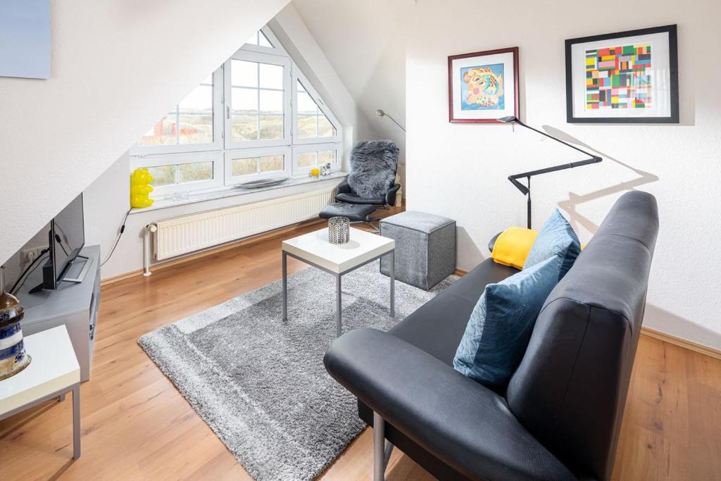 Una sala de estar con un sofá negro y una silla. en Haus Sanderling Träumchen, en Juist