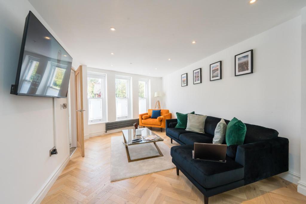a living room with a black couch and a tv at The Old Kiosk - Luxe 4 Bed House - Roath Park in Cardiff