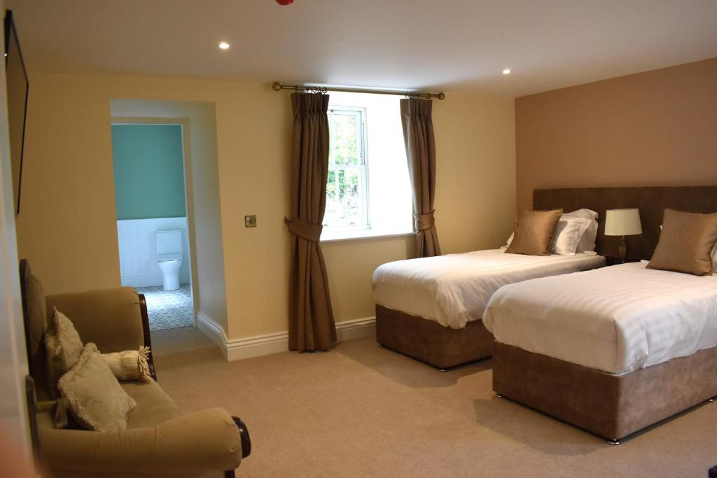 a bedroom with two beds and a chair and a window at Tobervilla Guest House in Caherdaniel