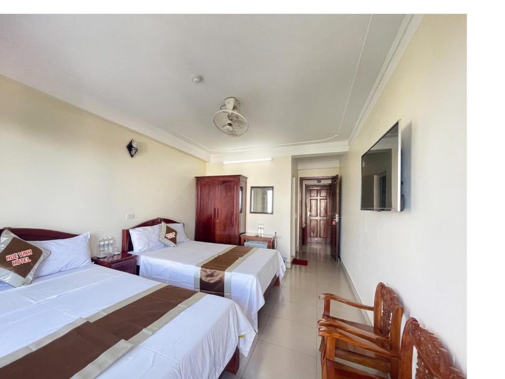 um quarto de hotel com duas camas e uma televisão em Khách Sạn Huệ Vinh em Thương Xà (2)