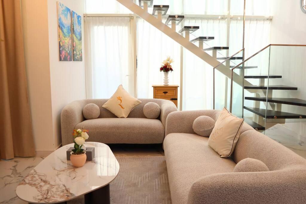 a living room with two couches and a staircase at Calm Oasis 2BR Apartment Masdar City in Abu Dhabi