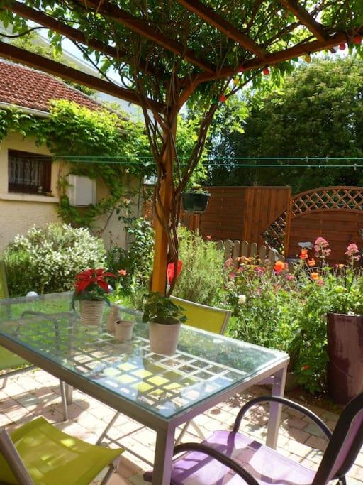 une table en verre avec des plantes dessus dans un jardin dans l'établissement Jolie maison, 3 chambres, jardin et parking, à Bagneux