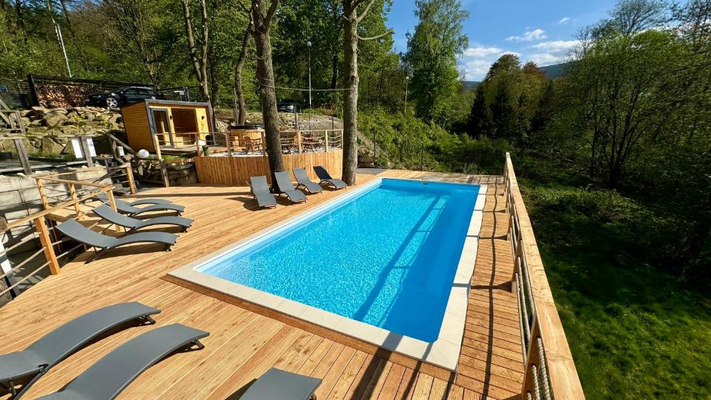 a swimming pool on a wooden deck with lounge chairs at Apartamenty Larice - basen, sauna i balia in Świeradów-Zdrój
