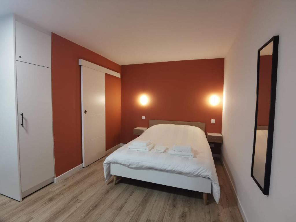 - une chambre avec un lit blanc et des murs orange dans l'établissement Studio Casa Amnéville, à Amnéville