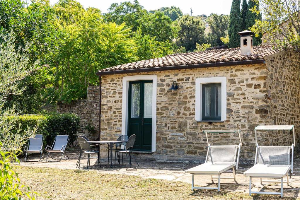 a stone house with a table and chairs in front of it at La Rimessa - ACrapa Mangia in Santa Maria di Castellabate