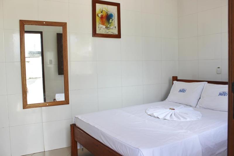 uma cama branca num quarto com um espelho em Hotel Paraty em Camaçari