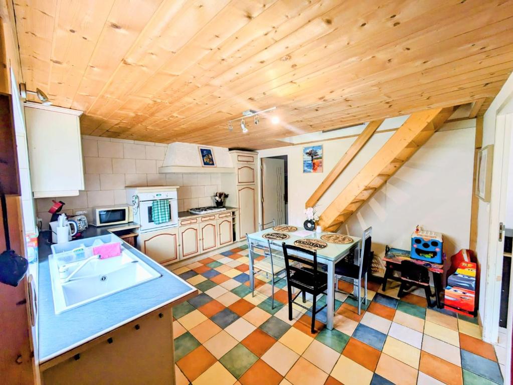 cocina con fregadero y mesa en una habitación en appart proche de la frontière, en Les Gras