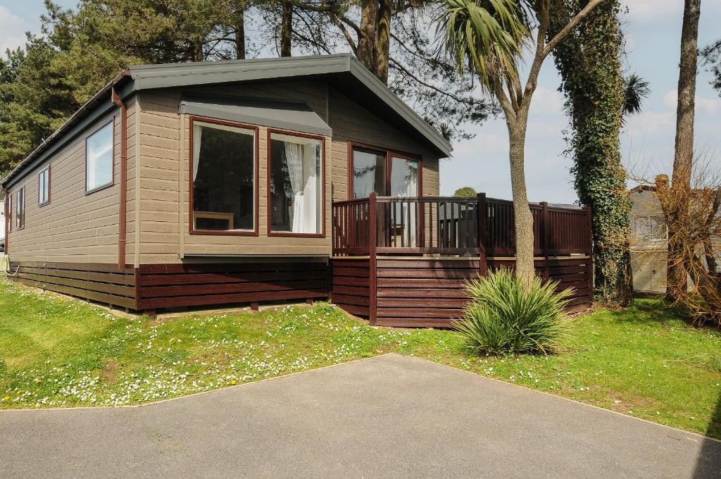 a tiny house with a porch and a deck at Lodge 15 at Landscove Holiday Park in Brixham