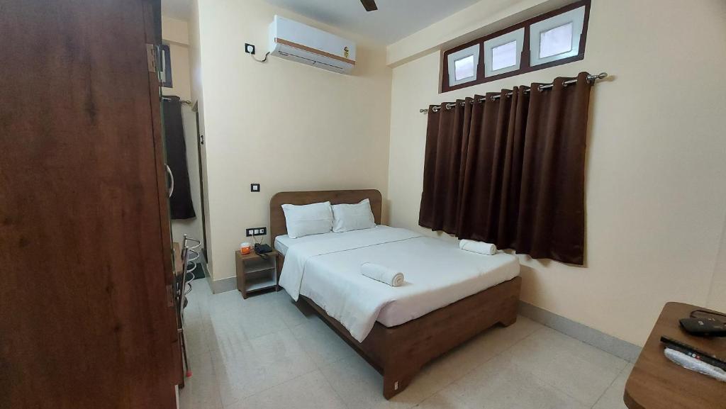 Schlafzimmer mit einem Bett mit weißer Bettwäsche und einem Fenster in der Unterkunft Hotel Hari Gayatri Regent in Guwahati