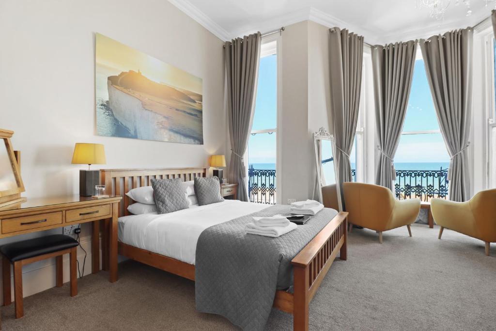 a hotel room with a bed and a desk andwindows at Beach Front Guest House in Eastbourne