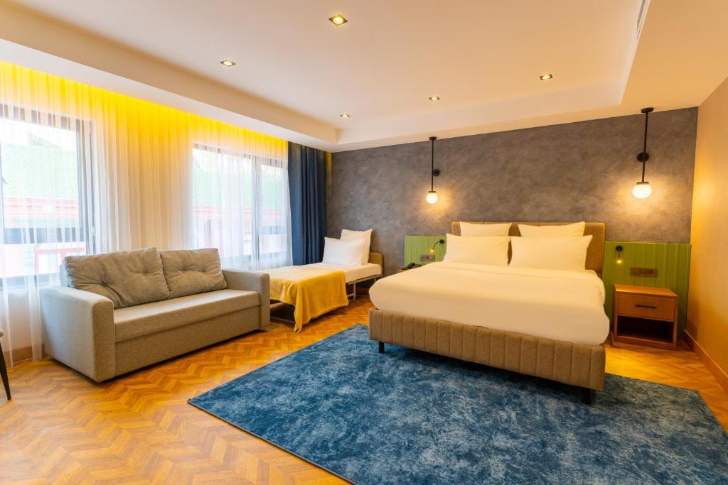 ein Hotelzimmer mit zwei Betten und einer Couch in der Unterkunft Q Style Hotel in Pelitli