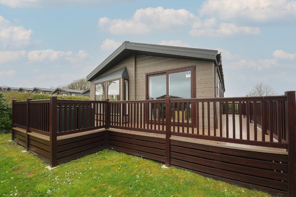 a small cabin with a wooden fence and grass at Lodge 73 at Riviera Bay Coastal Retreat in Brixham