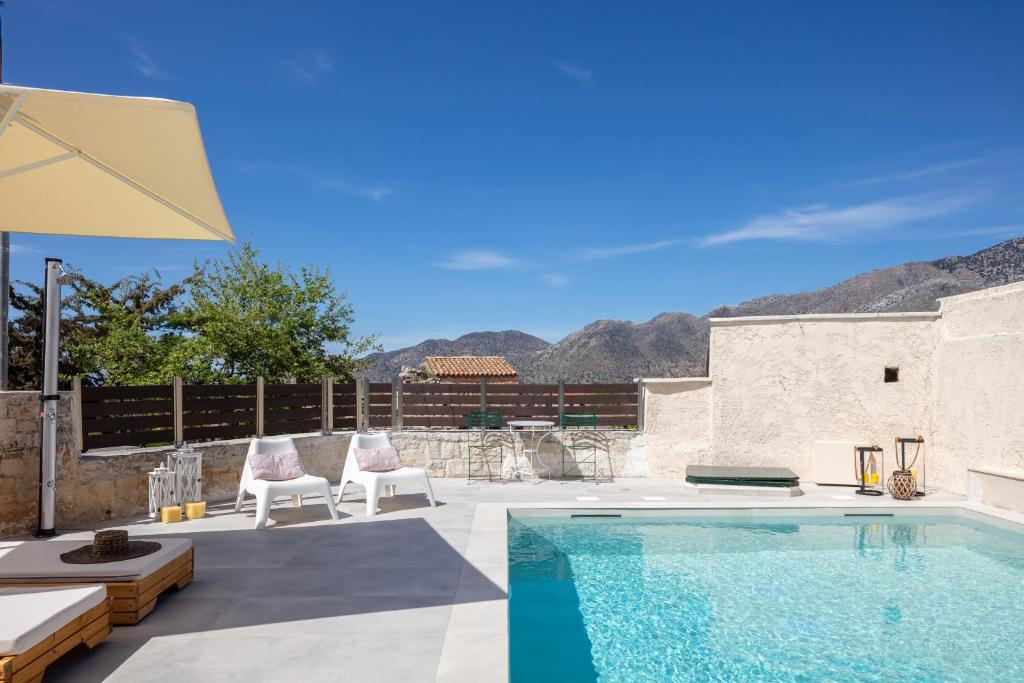 a swimming pool with two chairs and a umbrella at Captain's Hyatt in Garazo
