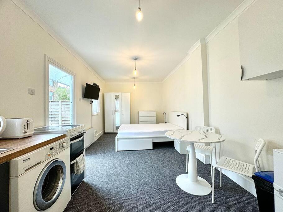 um quarto com uma cama, uma mesa e uma cozinha em Modern Studio 1 min Walk Station em Londres