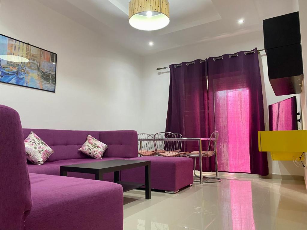 Appartement Urbaine, refuge et Cosy في Oued Laou: غرفة معيشة مع أثاث أرجواني وستائر أرجوانية