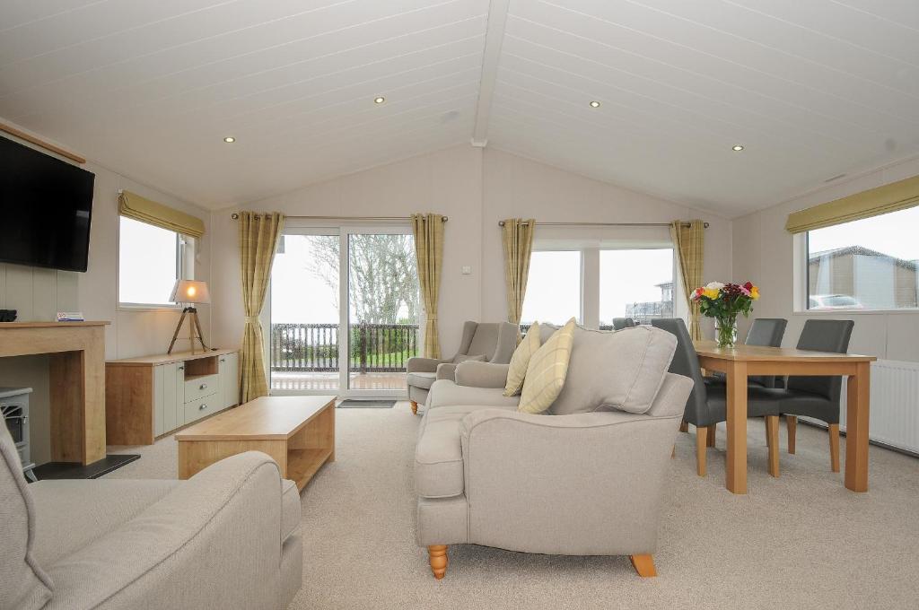 a living room with couches and a table and windows at Lodge 74 at Riviera Bay Coastal Retreat in Brixham