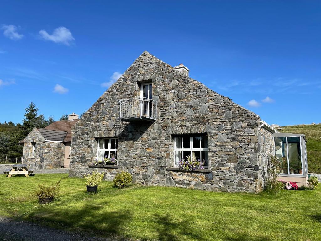 an old stone house with a balcony on a lawn at Shanakeever Farm - 2 Bedroom Apartment in Clifden