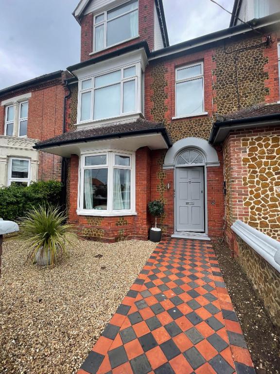 a red brick house with a cobblestone driveway at Belle-Vue Apartments in Hunstanton
