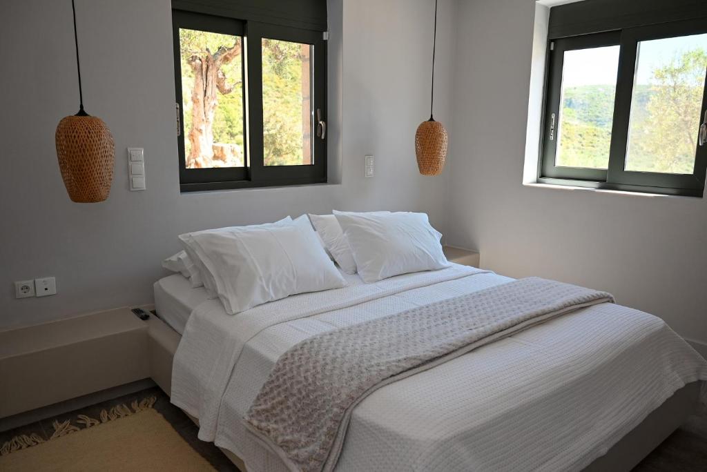 białe łóżko w sypialni z 2 oknami w obiekcie Athina's Stone House in Kardamyli w mieście Kardamyli