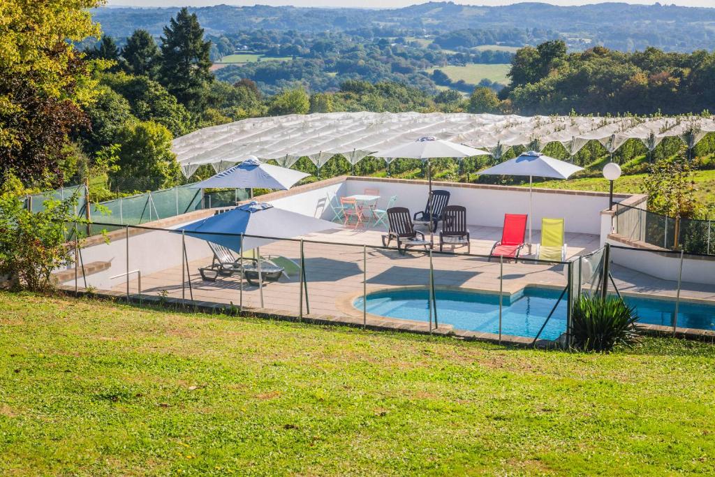 a house with a swimming pool with umbrellas at Relais du Bas Limousin in Sadroc