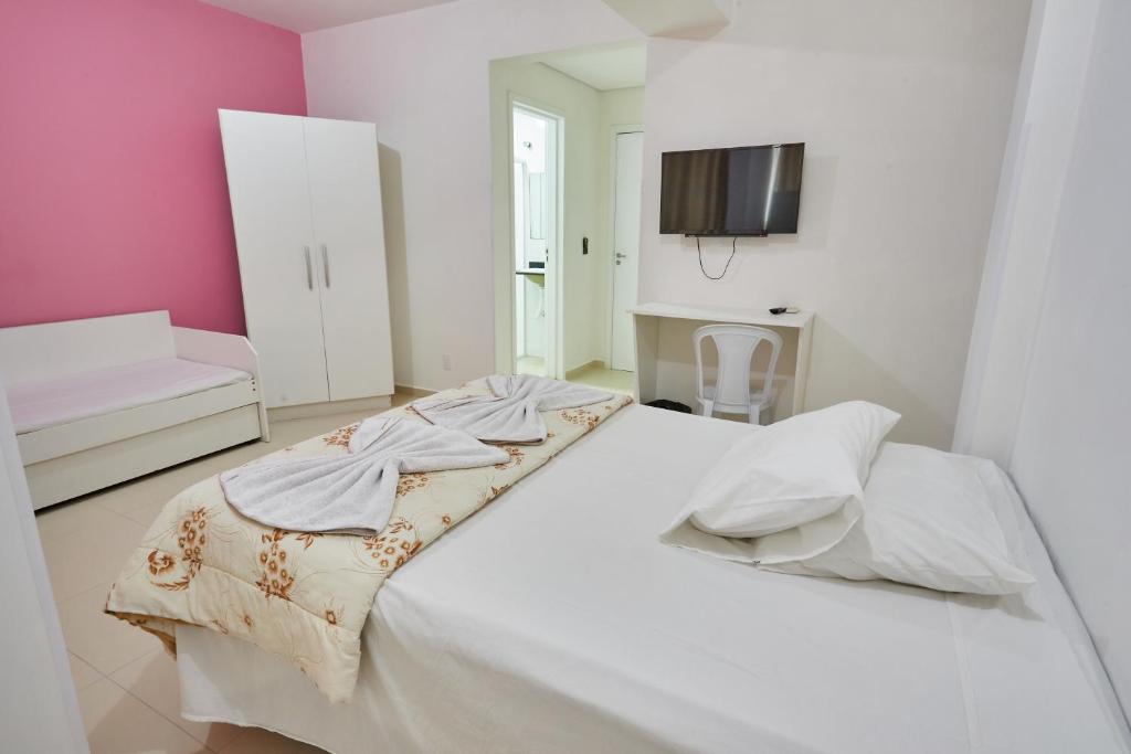 Cama blanca en habitación con paredes rosas en Monte Libano Apart Hotel, en Florianópolis