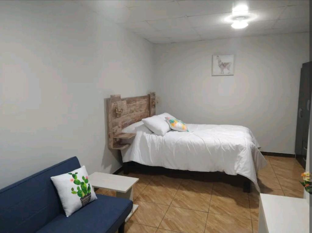 - une chambre avec un lit et un canapé bleu dans l'établissement Acogedor apartamento, à La Pampilla