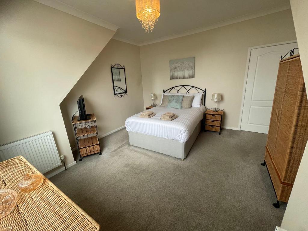 1 dormitorio con cama blanca y lámpara de araña en Belle-Vue Apartments, en Hunstanton
