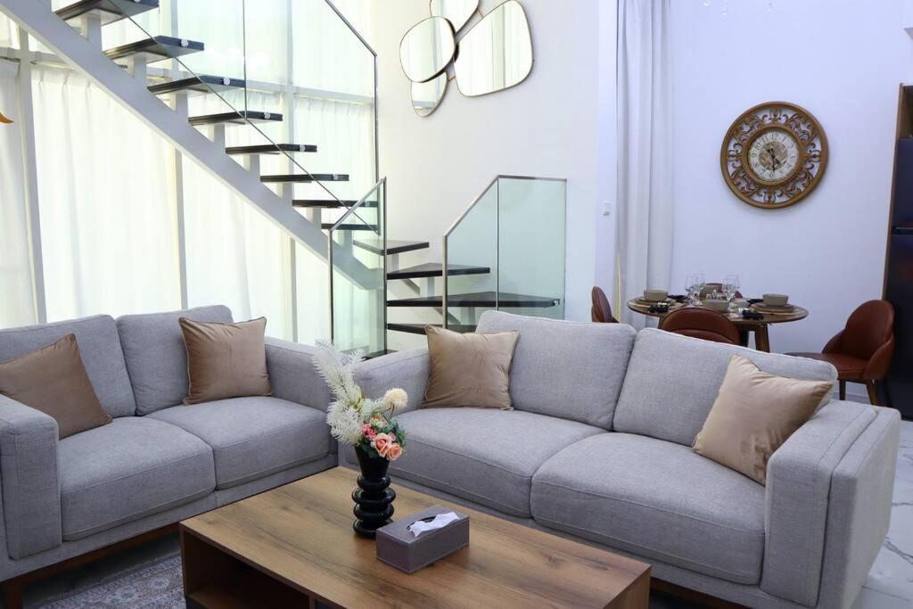a living room with a couch and a table at MasdarCity Bliss 2BR apartment in Abu Dhabi