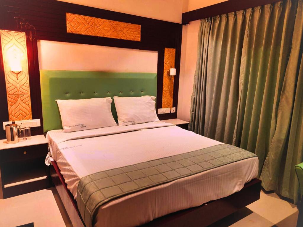 a bedroom with a bed with a green headboard at Hotel Harshanaa Elite in Kanyakumari