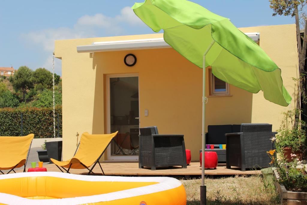 une maison avec des chaises jaunes et un parasol dans l'établissement Petite maison, cosy, sur les collines niçoises, à Nice