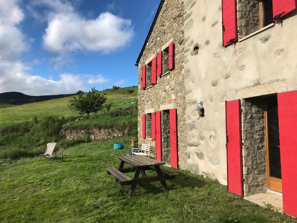 a picnic table in front of a building with red doors at Grande maison de vacances - Montagne Pyrénées in Planès