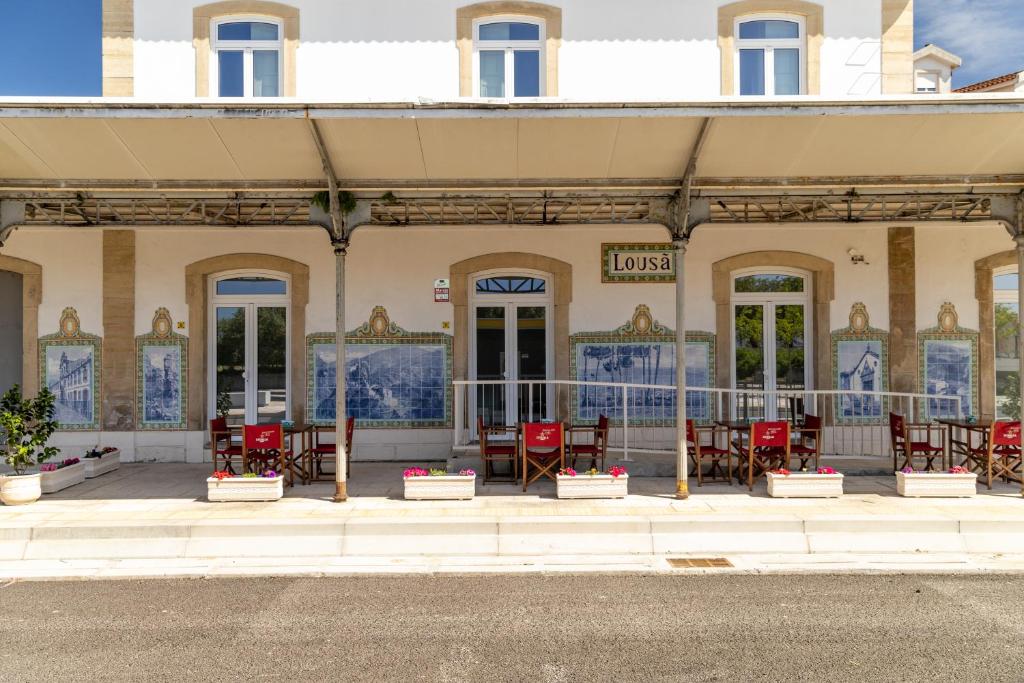 un edificio con tavoli e sedie di fronte ad esso di Lousã Estação AL a Coimbra